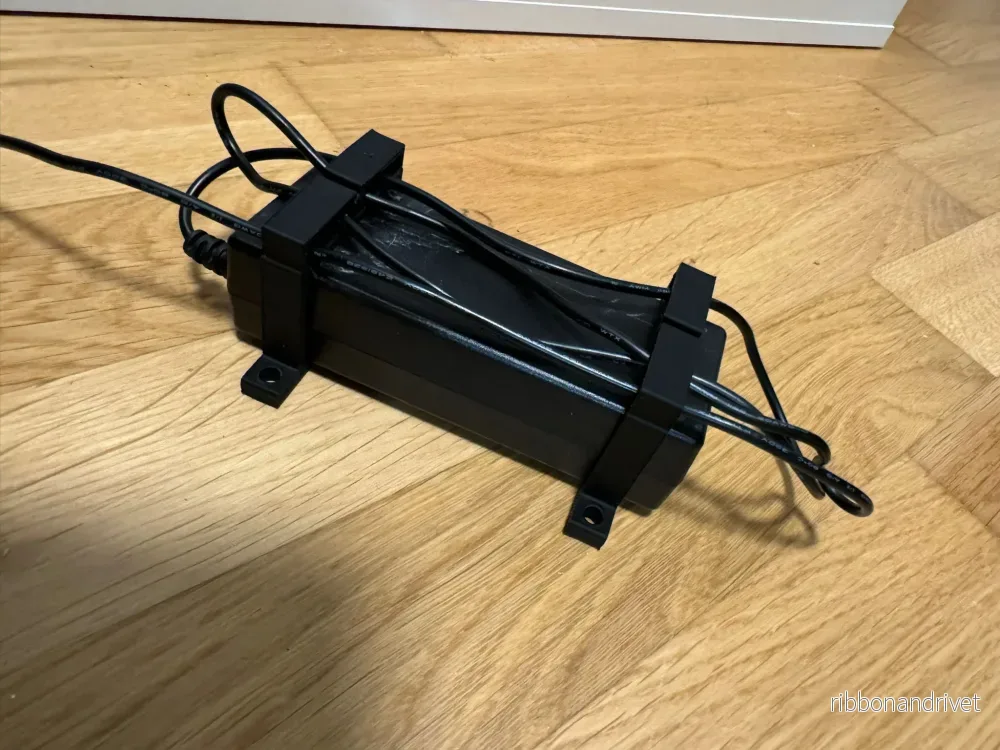 Parametrisk nätadapterhållare med kabelklämma